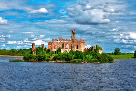 McDermott's Castle in the middle of the river and surrounded by trees with blue sky