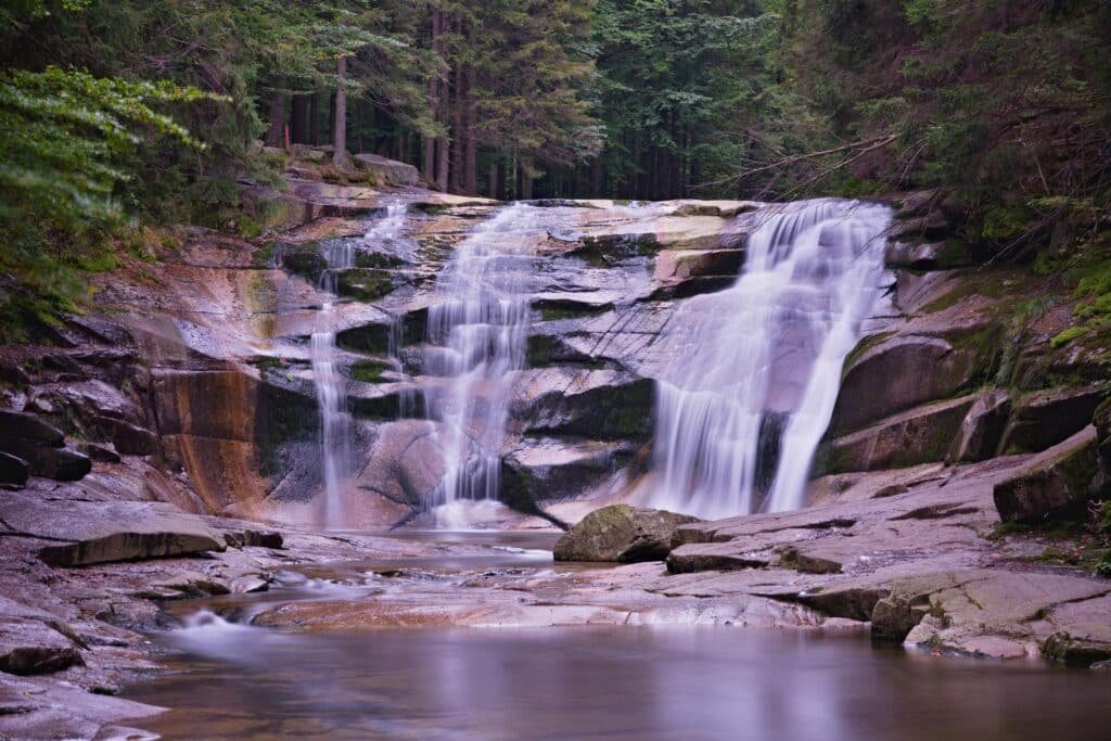 A tranquil waterfall cascading over rocks in a lush forest setting ideal for travel and nature themes
